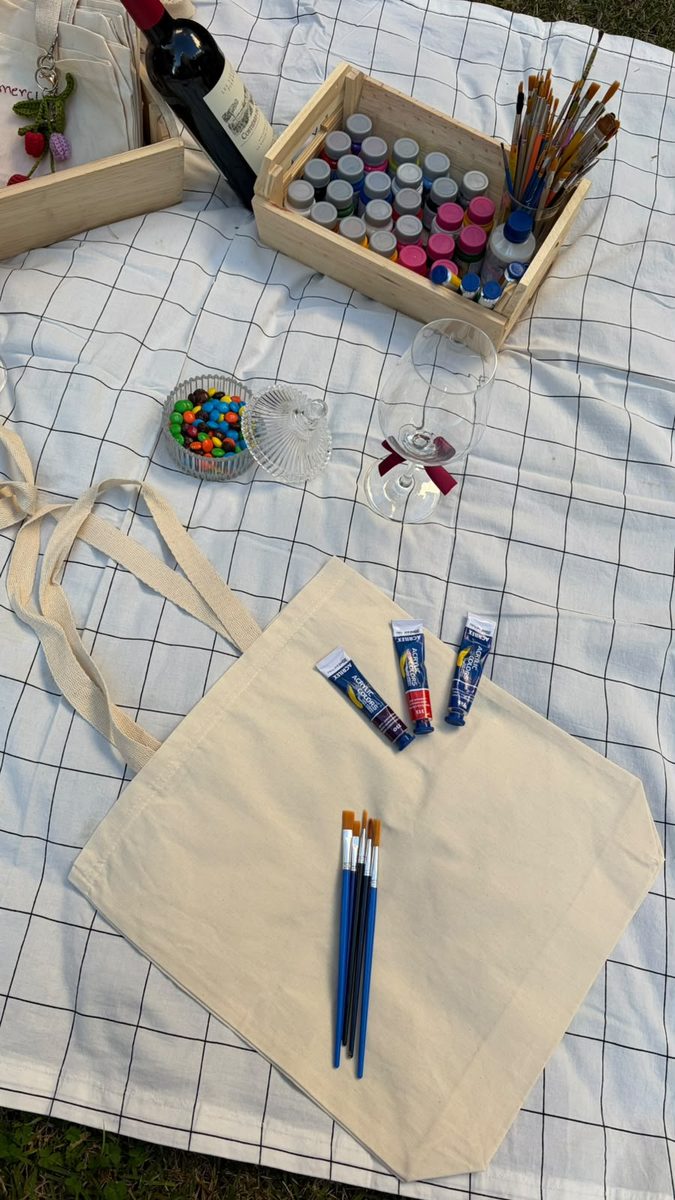 Mesa de pintura com paleta, ecobags ilustradas e materiais de arte